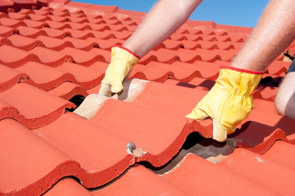 roofer installing red concrete roof tiles